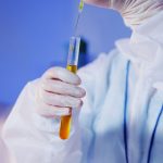 Cientista usando equipamento de proteção realiza um teste com tubo de ensaio em laboratório.