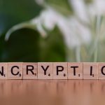 Blocos de madeira formam a palavra “encryption”, simbolizando criptografia e proteção de dados digitais.