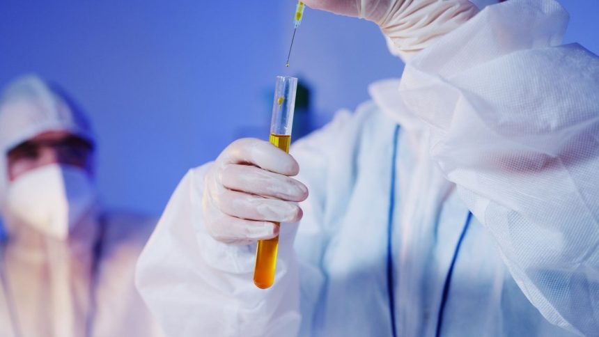 Cientista usando equipamento de proteção realiza um teste com tubo de ensaio em laboratório.