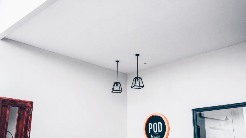 Interior minimalista de um espaço modular com luminárias geométricas e uma placa com a palavra “POD”.